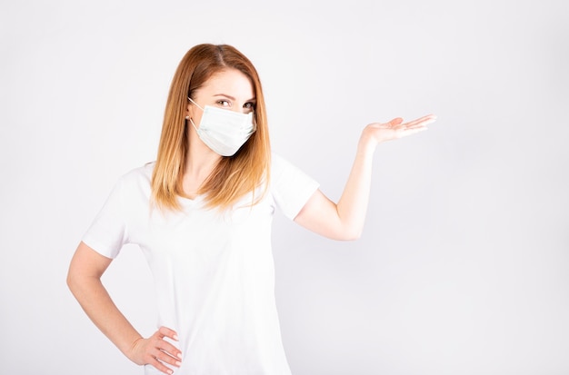 Beautiful caucasian young woman in white t-shirt with disposable face mask. Protection versus viruses and infection.