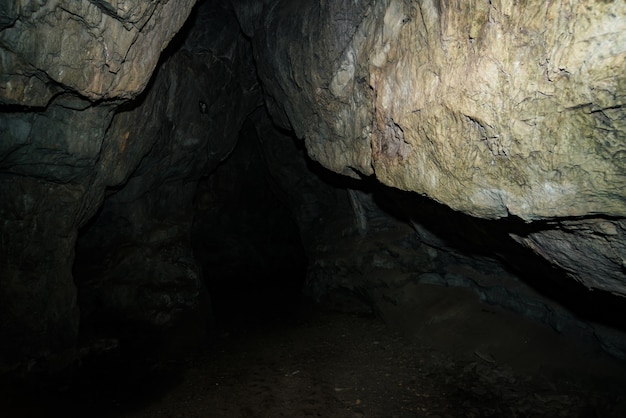 Beautiful cave. view from inside dark dungeon. textured walls\
of cave. dampness inside cave. light at end of tunnel.