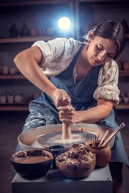 Beautiful ceramist woman molding a vase of clay on a potter's wheel. Handcraft.