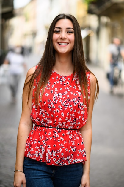 Beautiful charming young lady waking in a cuty street and looking back at the camera