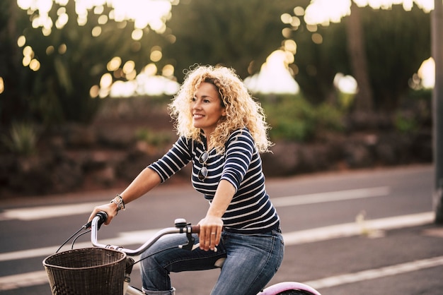 Beautiful and cheerful adult young woman enjoy bike ride in sunny urban outdoor leisure activity in the city