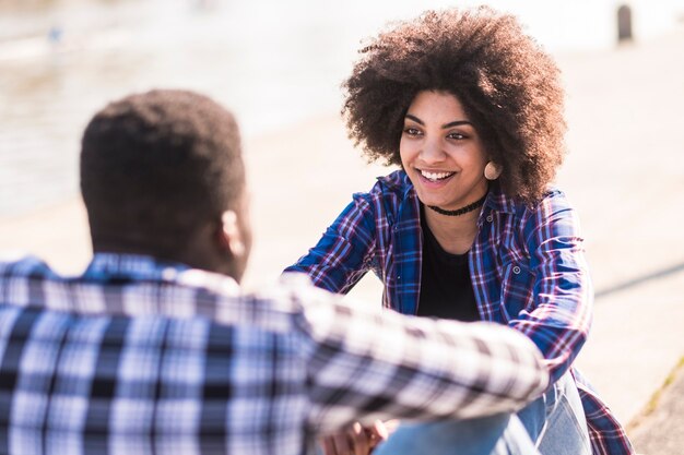 La bella ragazza afroamericana allegra si diverte e sorride con il ragazzo o un amico all'aperto