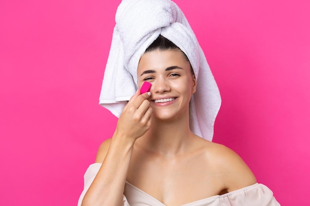 Photo beautiful cheerful attractive girl with a towel on her head holds a sponge in the form of a pink heart