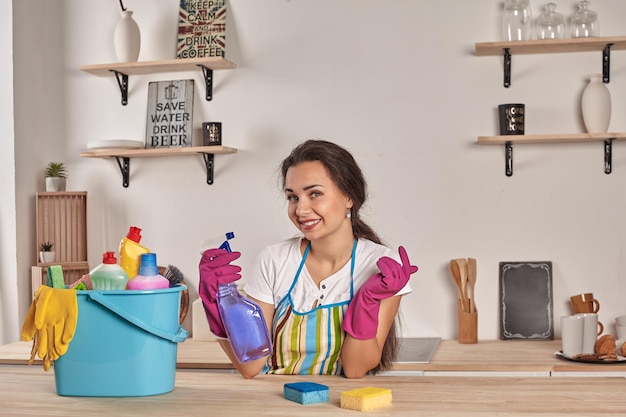 Beautiful cheerful brunette woman in gloves cleaning modern kitchen