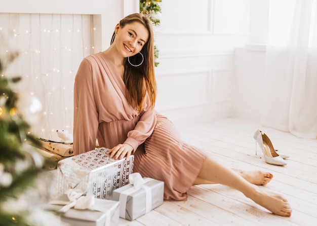 Beautiful cheerful happy young girl with christmas gifts on the background of a new year tree at home