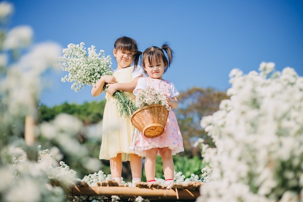 Beautiful and cheerful little kids playing together in the white flowers garden