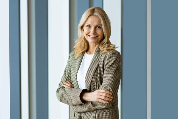 Beautiful and cheerful mature adult senior woman standing in the office - Portrait of successful corporate businesswoman with formal elegant dress