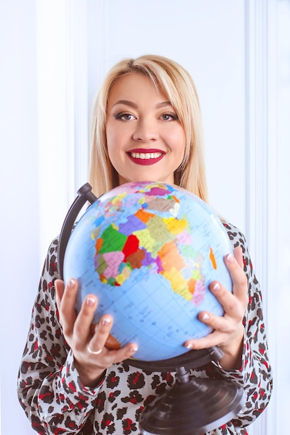 写真 彼女の手で地球を保持している美しい陽気な笑顔のブロンドの女性旅行代理店
