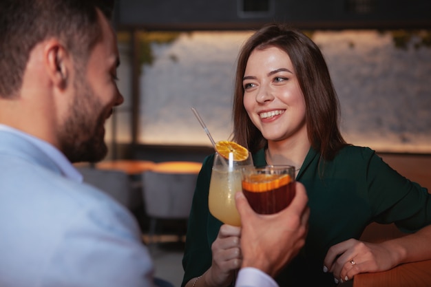 Beautiful cheerful woman enjoying night out with her boyfriend at cocktail bar