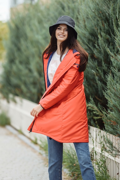 Bella donna allegra cammina lungo il vicolo in un cappotto autunnale.