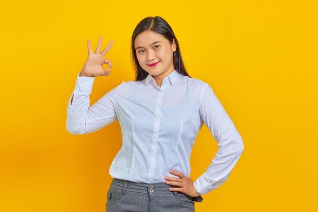 Beautiful and cheerful young business woman with confident face making okay sign with finger