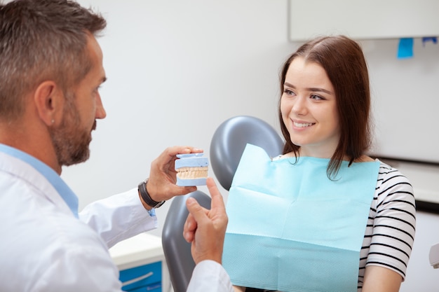 Beautiful cheerful young woman smiling at her dentist