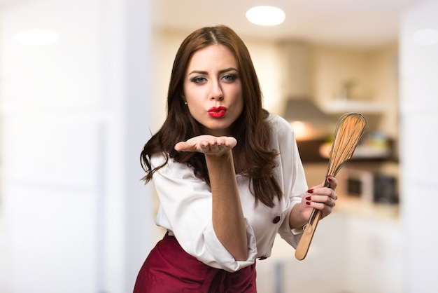 Beautiful chef woman sending a kiss on unfocused background