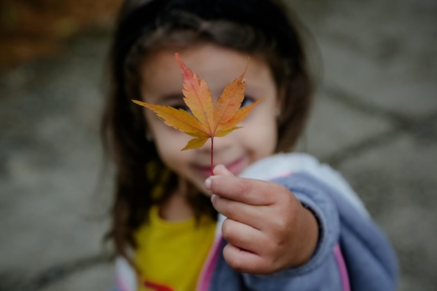 Bellissimo bambino che tiene in mano una foglia d'inverno