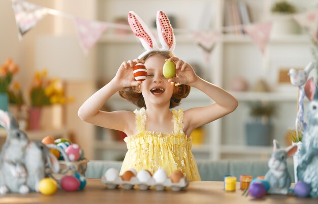 Beautiful child painting eggs Happy family preparing for Easter Cute little