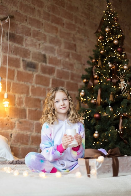 Beautiful child in pajamas with a Christmas gift