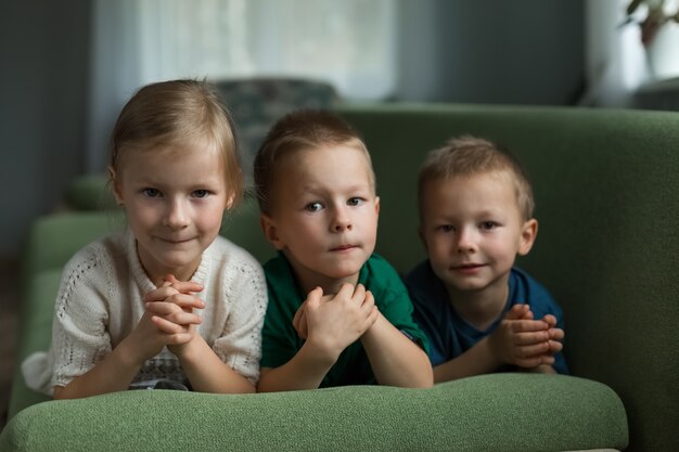 Beautiful children lie on the couch at home, looking at the camera. High quality.