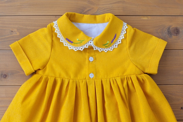 A beautiful children's dress made of natural cotton with embroidery of purple flowers on the collar. Lace on the collar. Children's clothing. A dress for a girl.