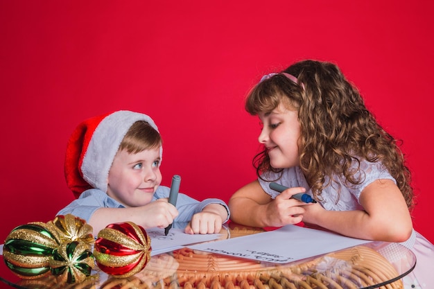 I bellissimi bambini scrivono una lettera a babbo natale. concetto di natale.