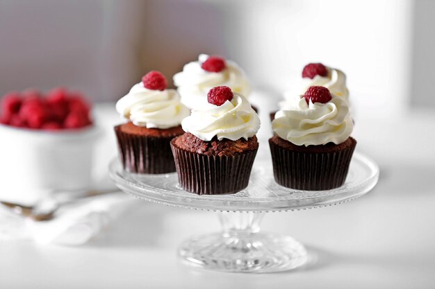 Beautiful chocolate cupcakes with cream and raspberry on table