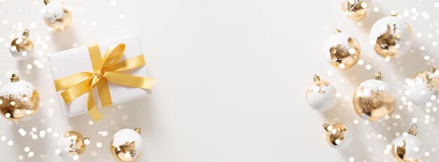Фото Красивый рождественский баннер с белым подарком, золотыми шарами и боке на белом фоне, рождественское поздравление