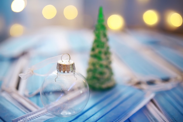 Photo beautiful christmas baubles on dark black background with medical mask. corona virus . new year on quarantine .flat lay design. copy space. square format. layout.