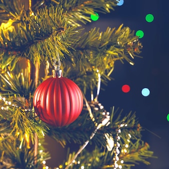 Bellissimo concetto di decorazione natalizia, pallina appesa all'albero di natale con punto luminoso scintillante, sfondo nero scuro sfocato, dettaglio macro, primo piano.