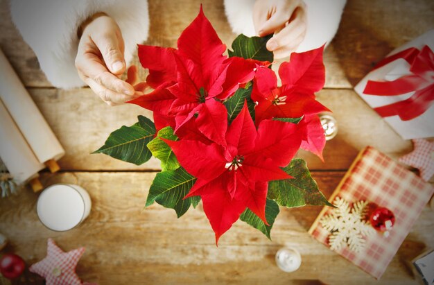 Beautiful Christmas flower with other decorations on wooden table close up