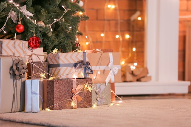 Beautiful Christmas gifts under fir tree on floor in room