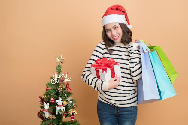 秋の背景にボックスとサンタの帽子の美しいクリスマスの女の子。