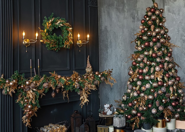 Bella ambientazione natalizia. camino a legna decorato con ghirlande e candele, albero di natale decorato con palline, stelle, pigne, palline in stile vintage.