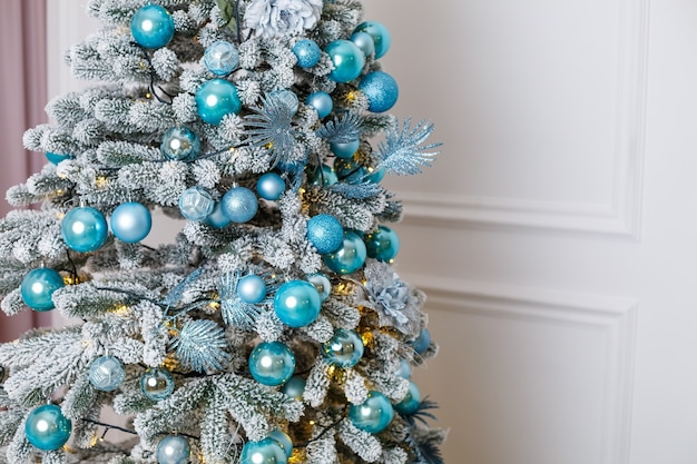 사진 스튜디오, 침실, 새해 장식의 겨울 내부에 있는 아름다운 크리스마스 트리. 파란 공 크리스마스 장난감입니다. 새해가 곧