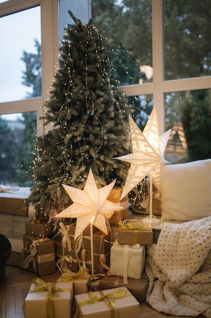 큰 창으로 선물 아름 다운 크리스마스 트리. 겨울이오고있다. 베개가 달린 격자 무늬