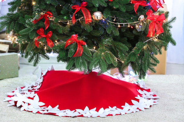 Beautiful Christmas tree with skirt in room