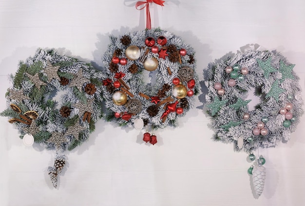 Beautiful Christmas wreaths made by professional florist hanging on light wall