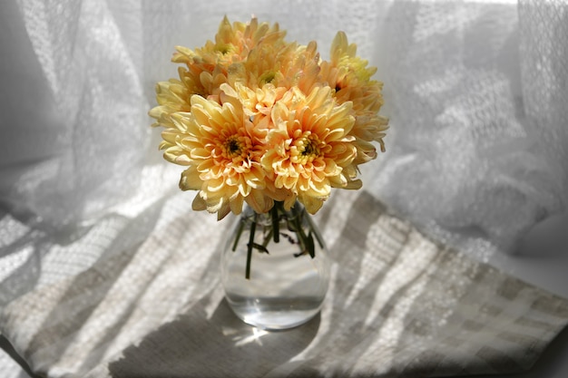 Beautiful chrysanthemums in vase on fabric