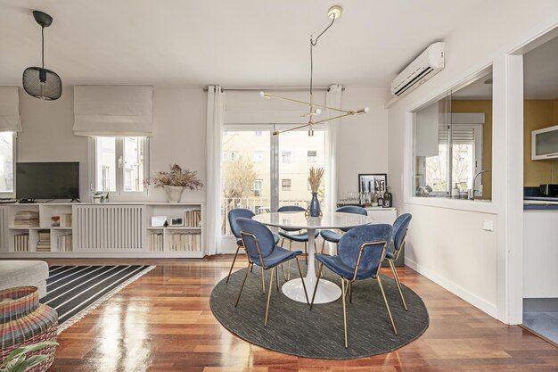 Photo beautiful circular dining table painted in gloss white with blue velvet upholstered chairs surrounding it