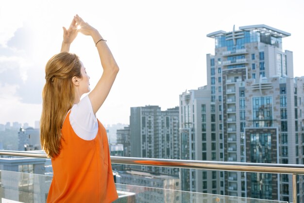 美しい街。手を上げて街を眺める素敵なうれしそうな女性