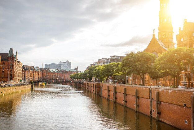 Bella vista del paesaggio urbano sul canale d'acqua con la vecchia chiesa nella città di amburgo durante il tramonto in germania