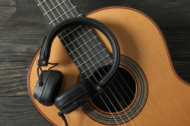 Beautiful classic guitar with headphones on wooden table, closeup