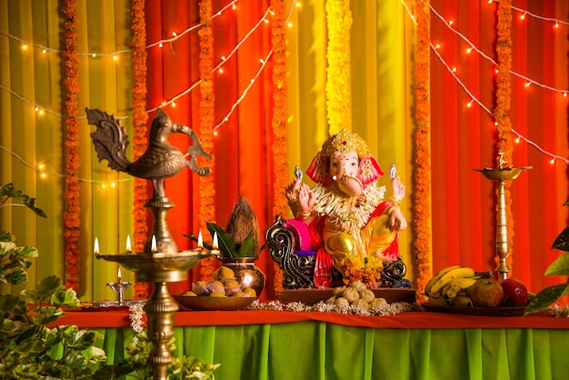 ガネーシュフェスティバルのお祝いやプージャのためにカラフルなカーテンとマリーゴールドの花輪で飾られたインドのヒンドゥー教の神、ガネーシャ卿の美しい粘土像または偶像