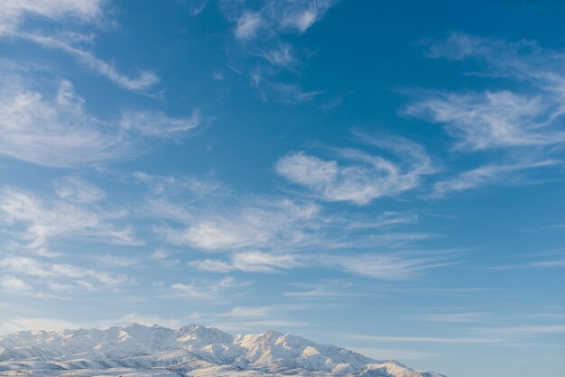 Красивые облака против голубого неба над горами Тянь-Шаня зимой в Узбекистане