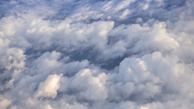 澄んだ青い空と美しい雲景。航空機の窓から見た白い雲の上のパノラマ。飛行機の窓からの眺め