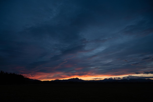 Beautiful cloudy sky coloured in red and orange colours of the sunset over silhouetted nature