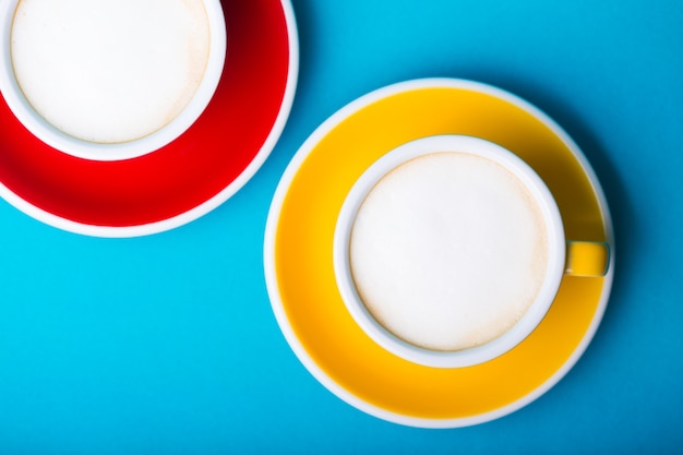 Beautiful coffee yellow and red cup with cappuccino on blue background