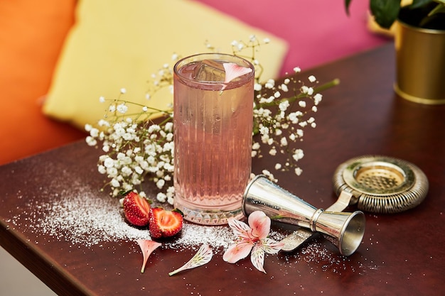 Beautiful cold cocktail and flowers on table