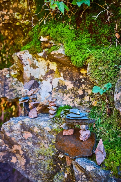 Красивая коллекция небольших каменных стеков на фоне скал, покрытых мхом и лишайником