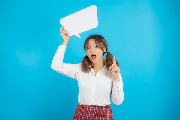 Beautiful college girl holding white idea board top of her head and points finger on it. High quality photo