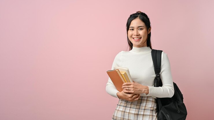 Photo beautiful college student holding textbooks and carrying bag pack on pink isolated background