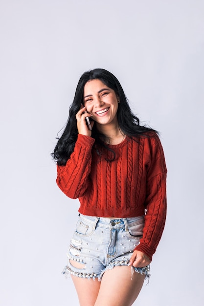 Красивая колумбийка улыбается и развлекается со своим мобильным телефоном во время разговора
